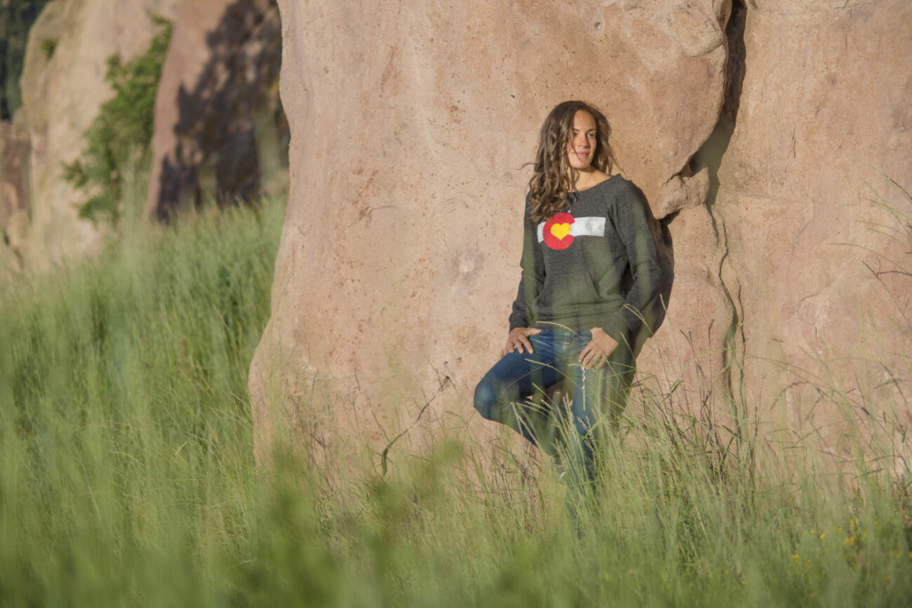 woman in sweatshirt leaning against a rock